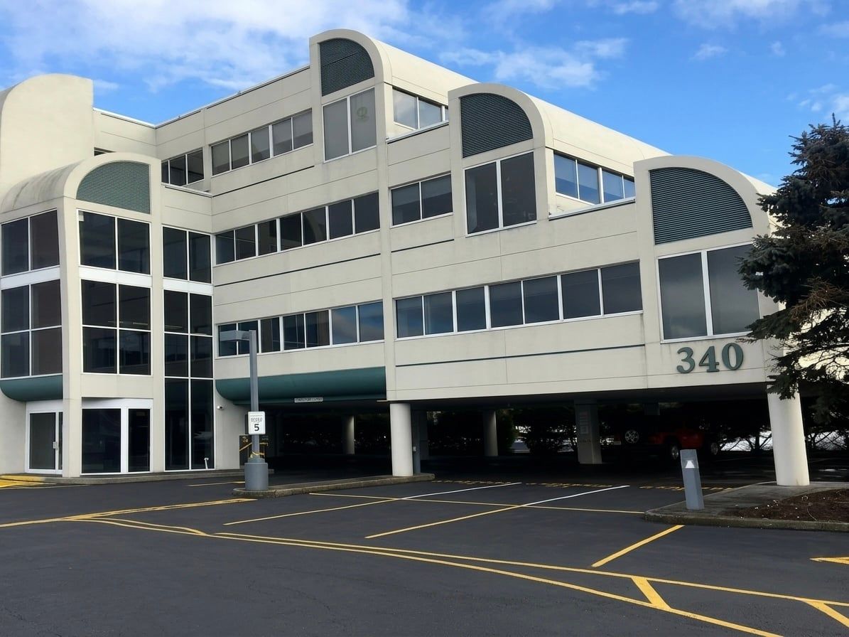 Three-story office building with the number 340 on its facade, seen from the parking lot